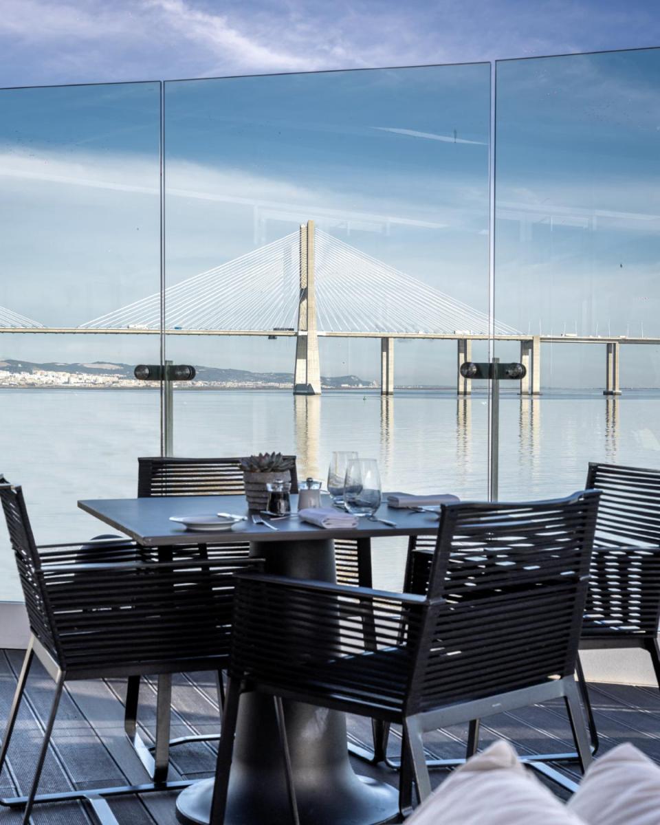uma mesa com cadeiras e uma ponte ao fundo em MYRIAD by SANA Hotels em Lisboa