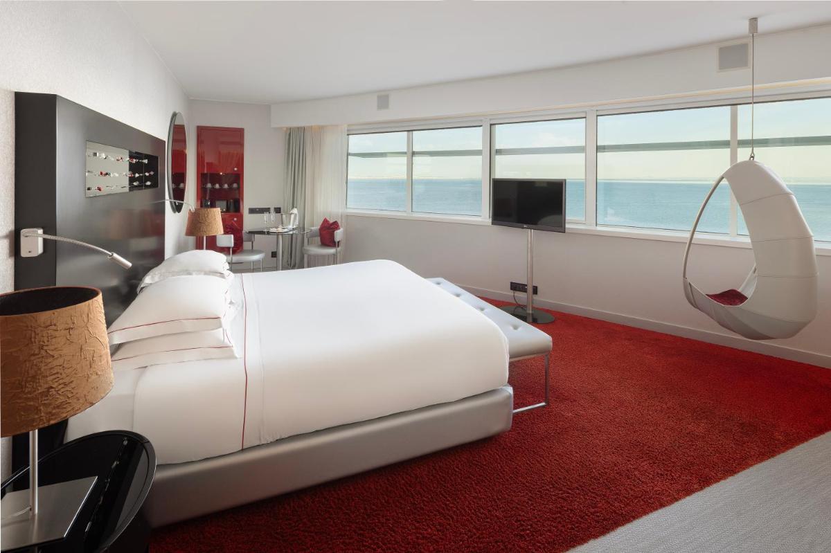 um quarto com uma grande cama branca e um espelho em MYRIAD by SANA Hotels em Lisboa