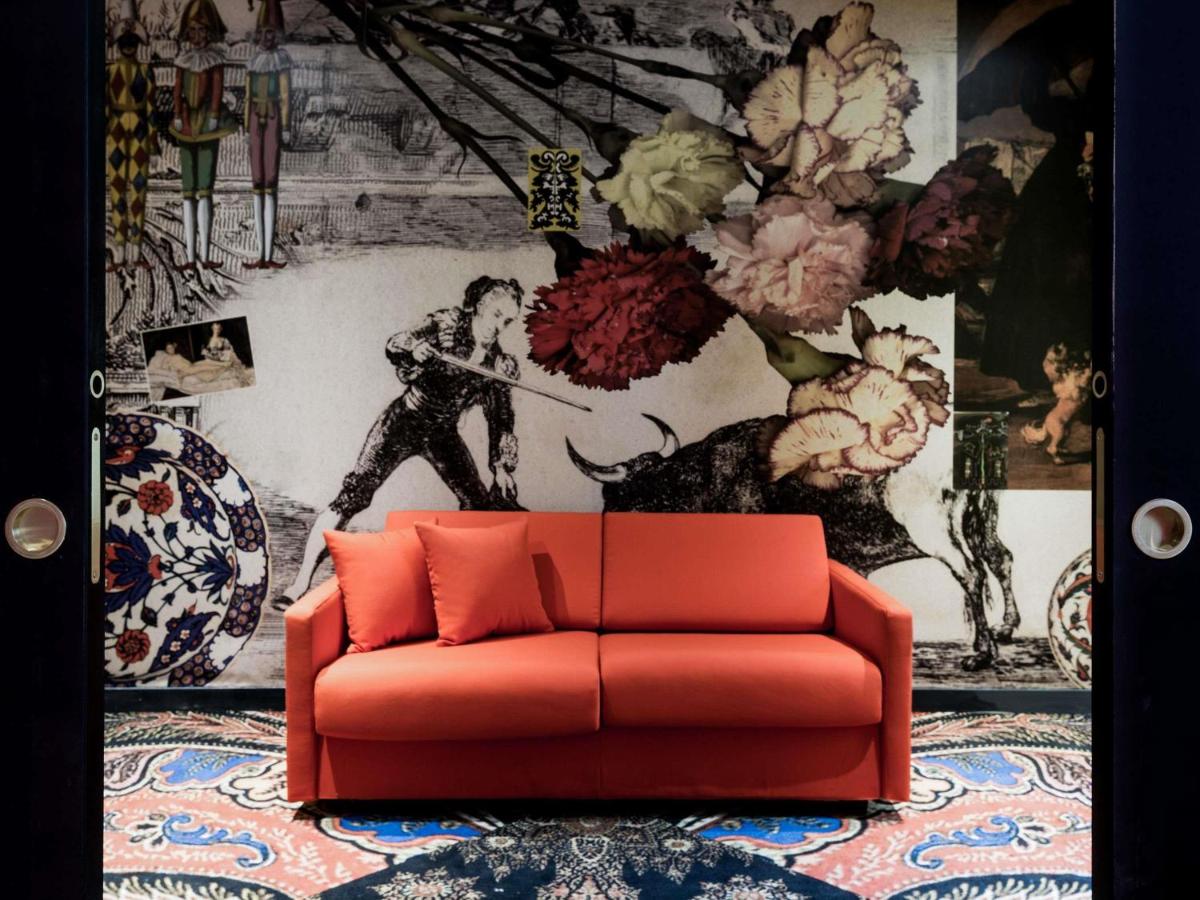 un canapé rouge dans une pièce avec un mur dans l'établissement Jules César Hotel & Spa Arles - MGallery Collection, à Arles