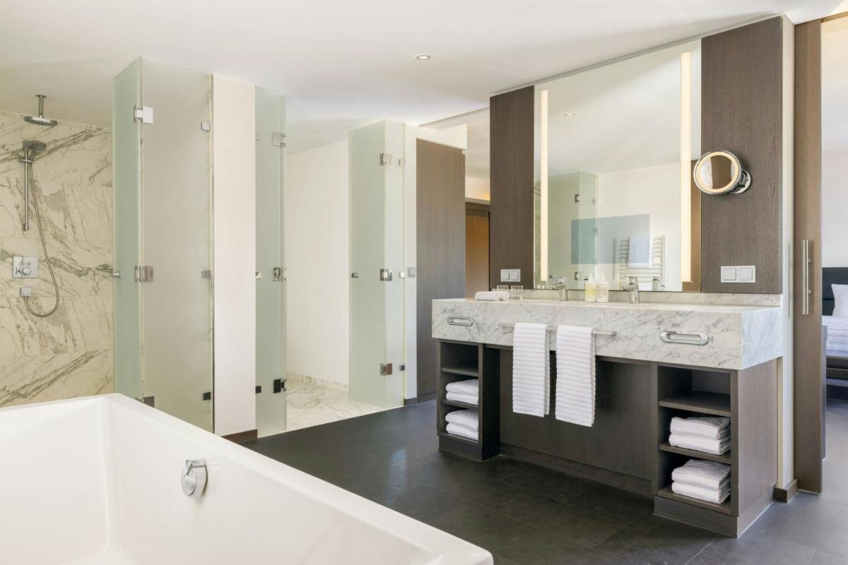 ein Badezimmer mit Badewanne und großem Spiegel in der Unterkunft Le Méridien Frankfurt in Frankfurt am Main