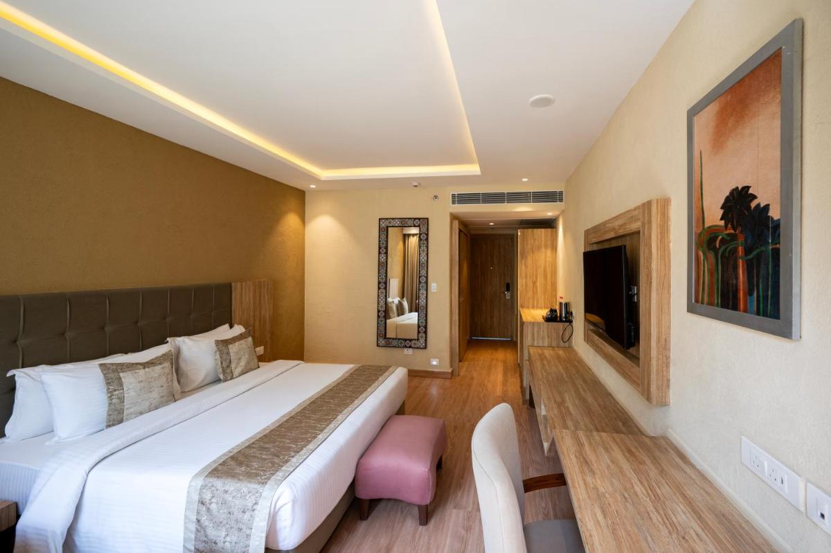 a hotel room with a large bed and a tv at Essentia Luxury Resort & Spa Udaipur in Udaipur