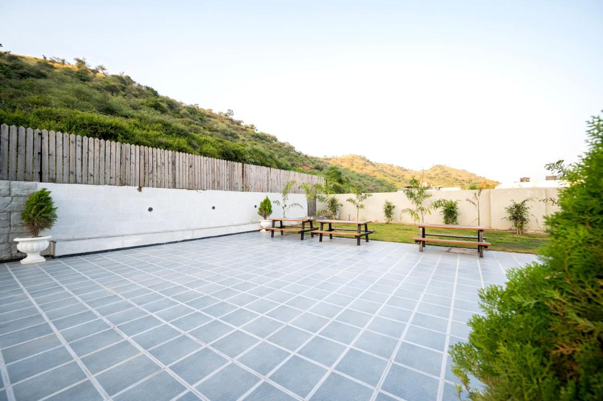 a patio with two benches and a fence at Essentia Luxury Resort & Spa Udaipur in Udaipur