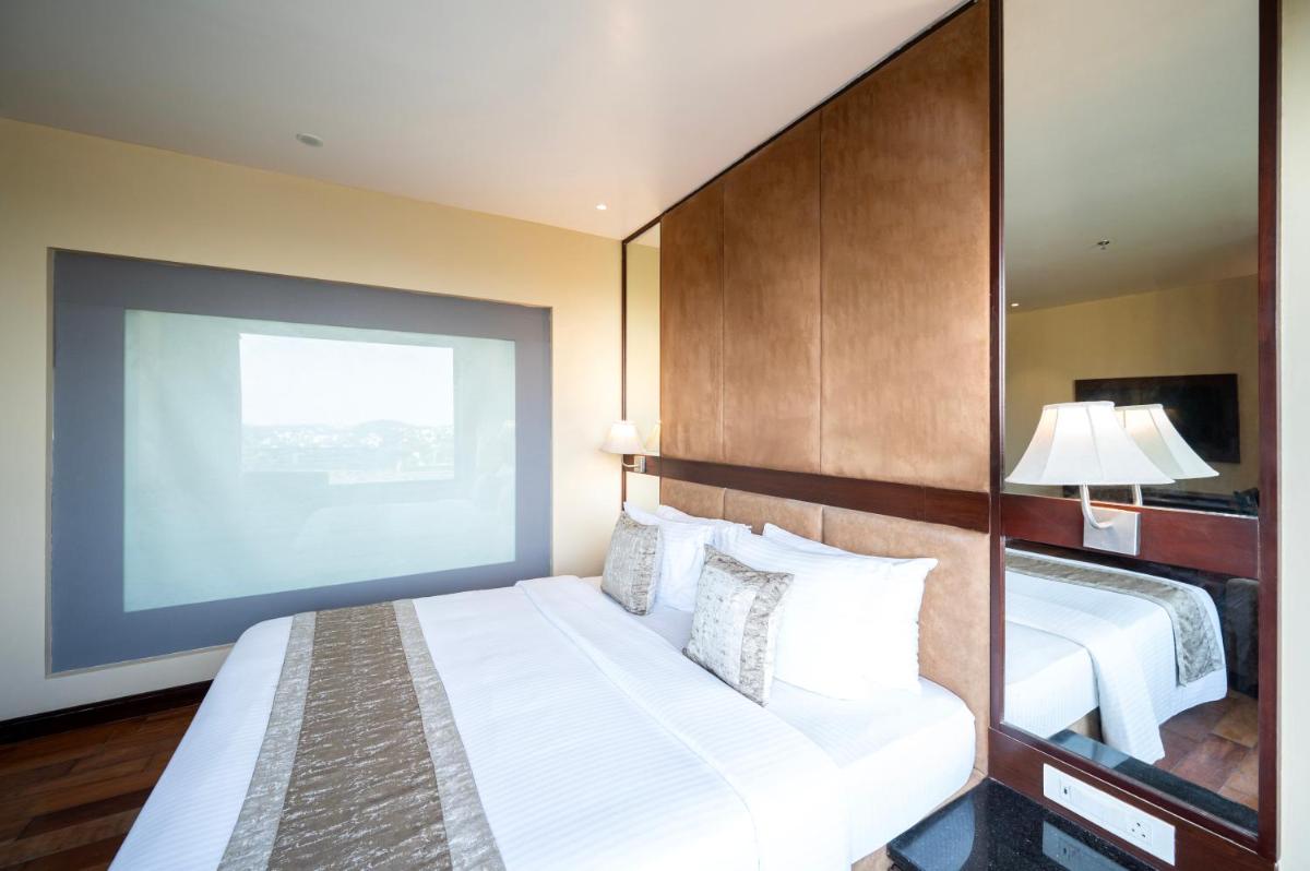 a hotel room with two beds and a large screen at Essentia Luxury Resort & Spa Udaipur in Udaipur