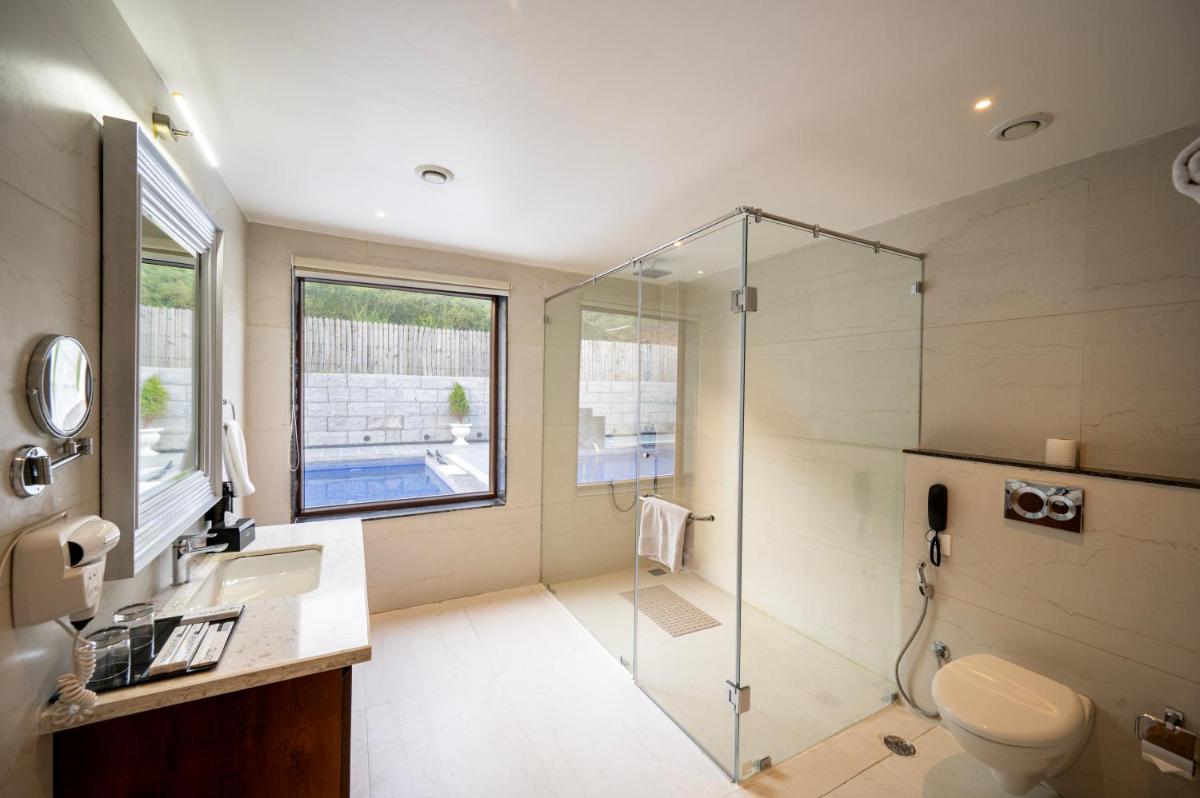 a bathroom with a shower and a toilet and a sink at Essentia Luxury Resort & Spa Udaipur in Udaipur