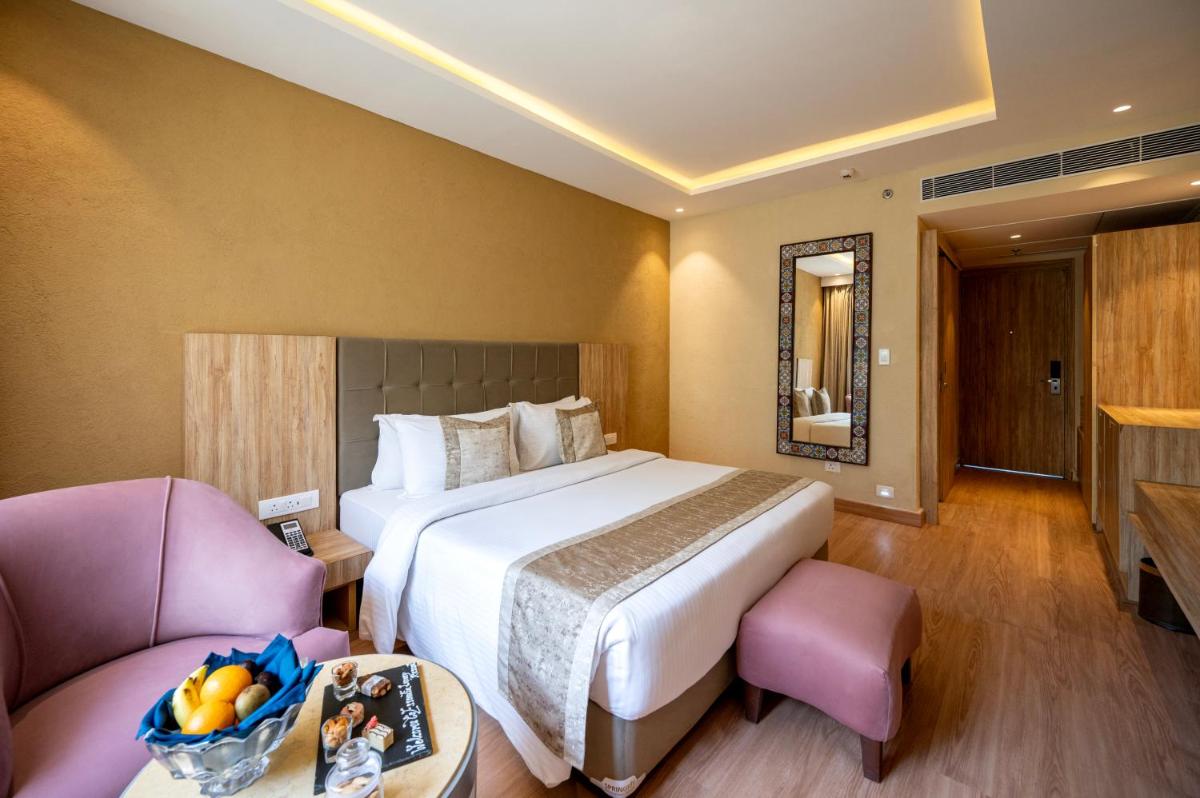 a hotel room with a large bed and a chair at Essentia Luxury Resort & Spa Udaipur in Udaipur