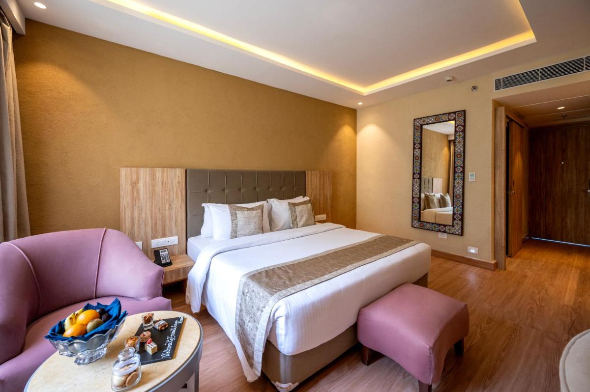 a hotel room with a large bed and two chairs at Essentia Luxury Resort & Spa Udaipur in Udaipur