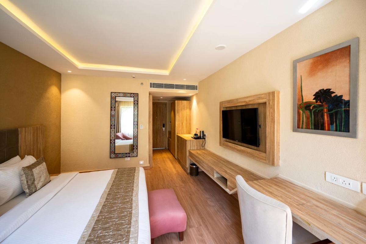 a hotel room with a bed and a tv at Essentia Luxury Resort & Spa Udaipur in Udaipur