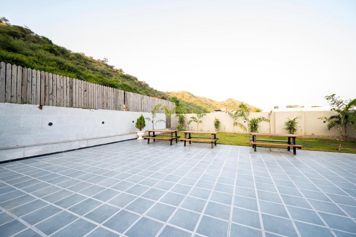 a patio with two benches and a fence at Essentia Luxury Resort & Spa Udaipur in Udaipur