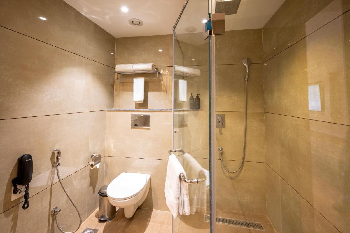a bathroom with a toilet and a glass shower at Essentia Luxury Resort & Spa Udaipur in Udaipur