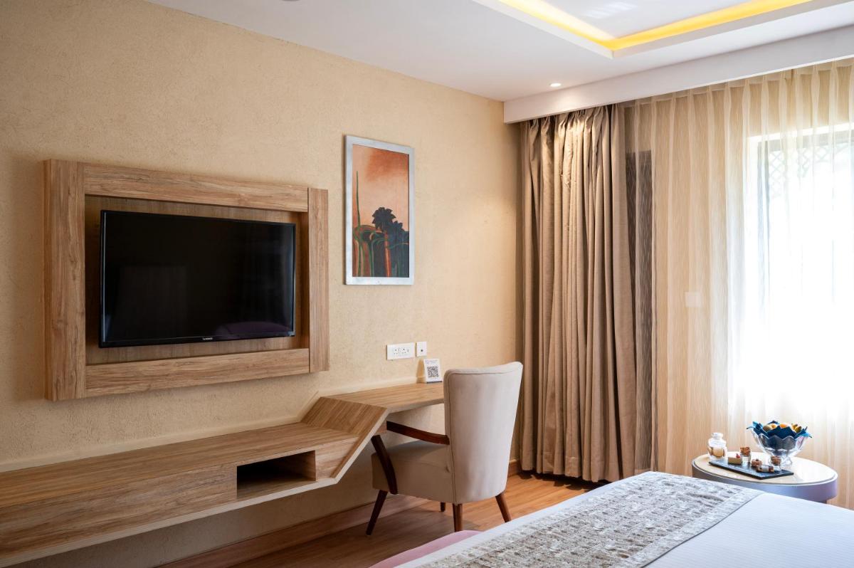 a hotel room with a desk and a television at Essentia Luxury Resort & Spa Udaipur in Udaipur