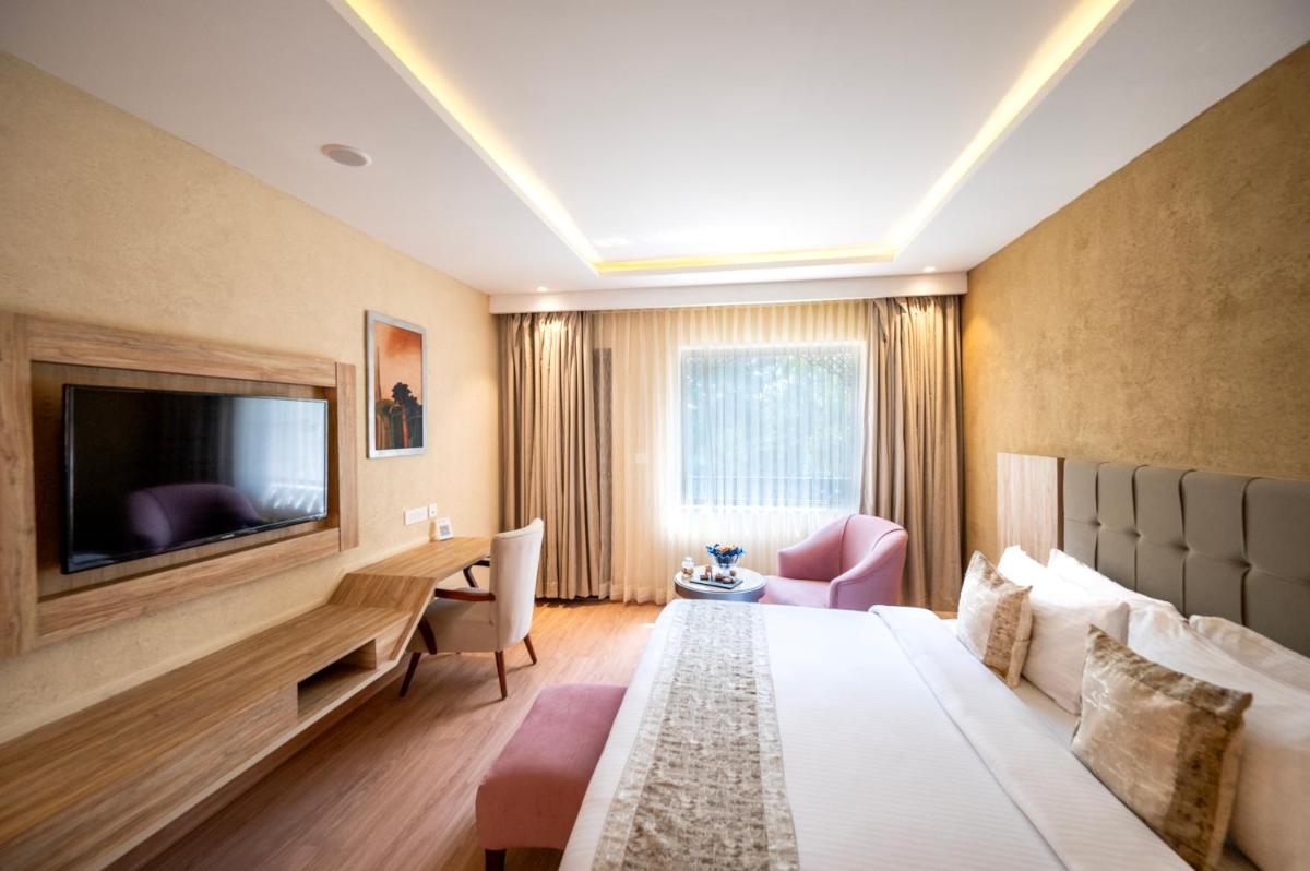 a hotel room with a bed and a flat screen tv at Essentia Luxury Resort & Spa Udaipur in Udaipur