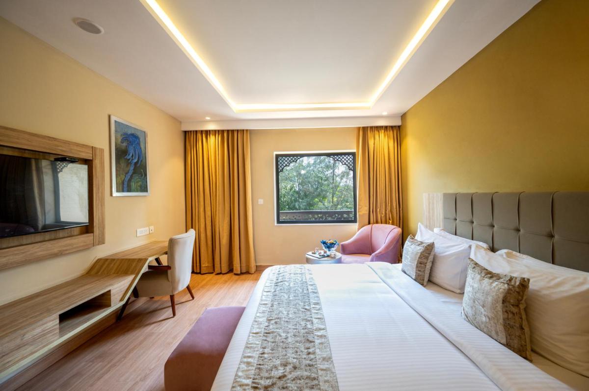 a hotel room with a large bed and a desk at Essentia Luxury Resort & Spa Udaipur in Udaipur