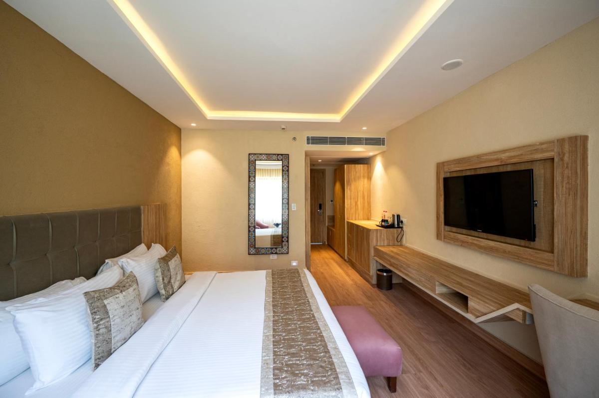 a hotel room with a bed and a flat screen tv at Essentia Luxury Resort & Spa Udaipur in Udaipur