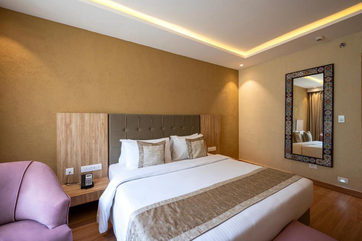 a bedroom with a large bed and a mirror at Essentia Luxury Resort & Spa Udaipur in Udaipur