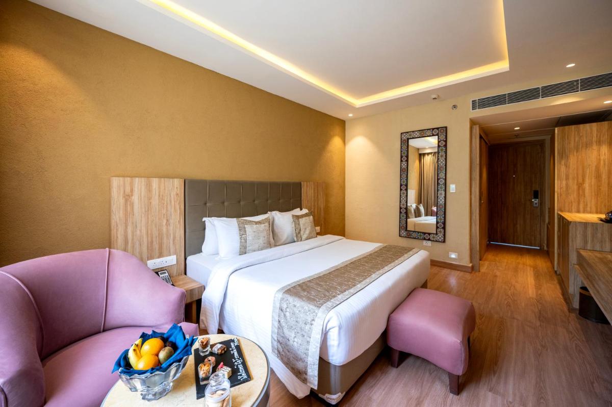 a hotel room with a large bed and two chairs at Essentia Luxury Resort & Spa Udaipur in Udaipur