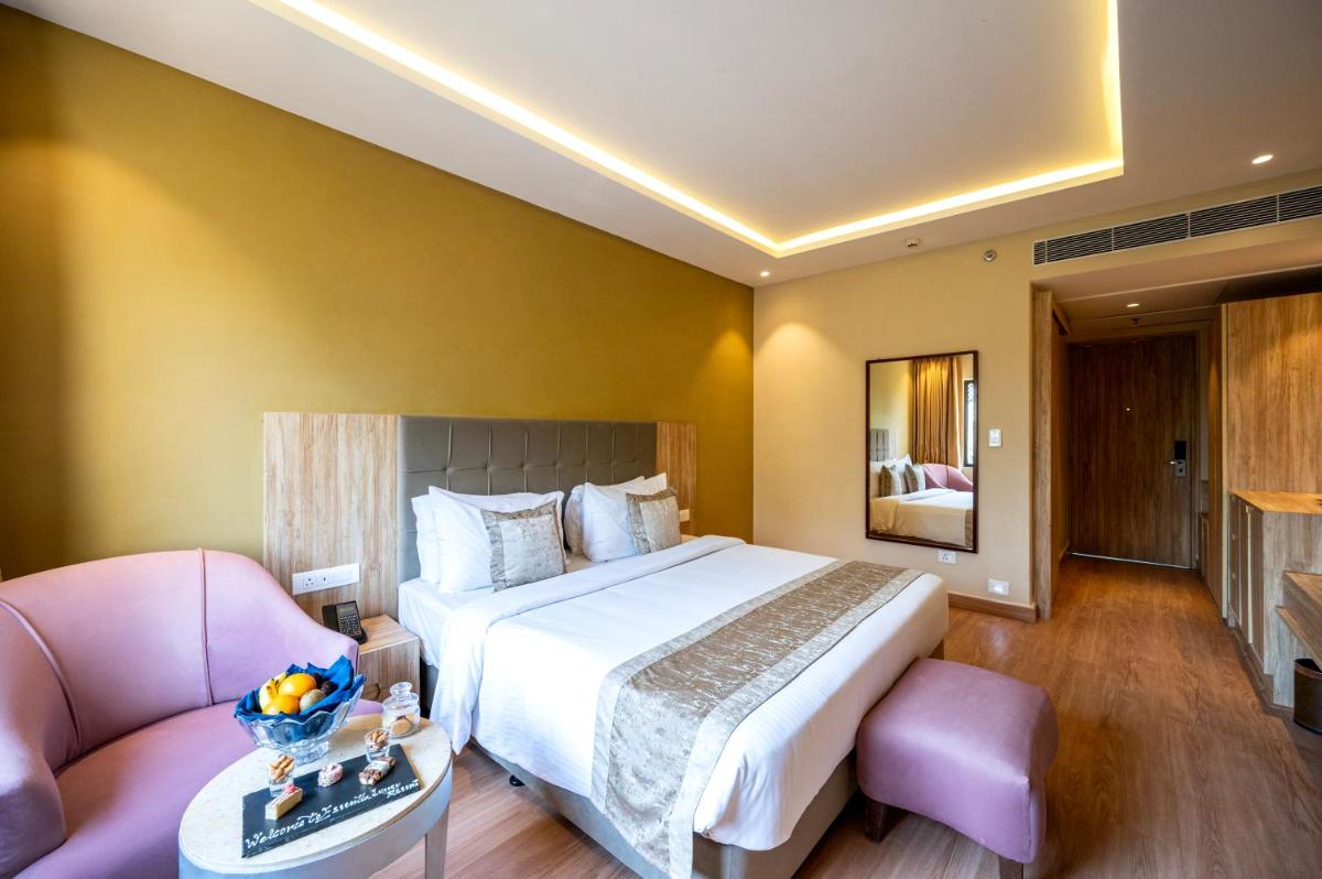 a bedroom with a large bed and a pink couch at Essentia Luxury Resort & Spa Udaipur in Udaipur