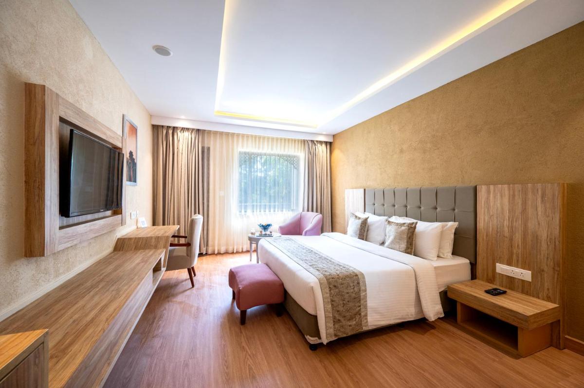 a hotel room with a bed and a television at Essentia Luxury Resort & Spa Udaipur in Udaipur