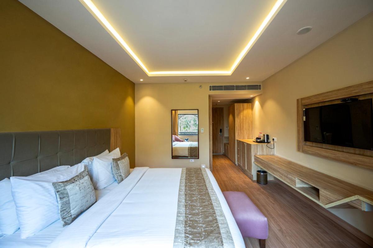 a bedroom with a large bed and a flat screen tv at Essentia Luxury Resort & Spa Udaipur in Udaipur