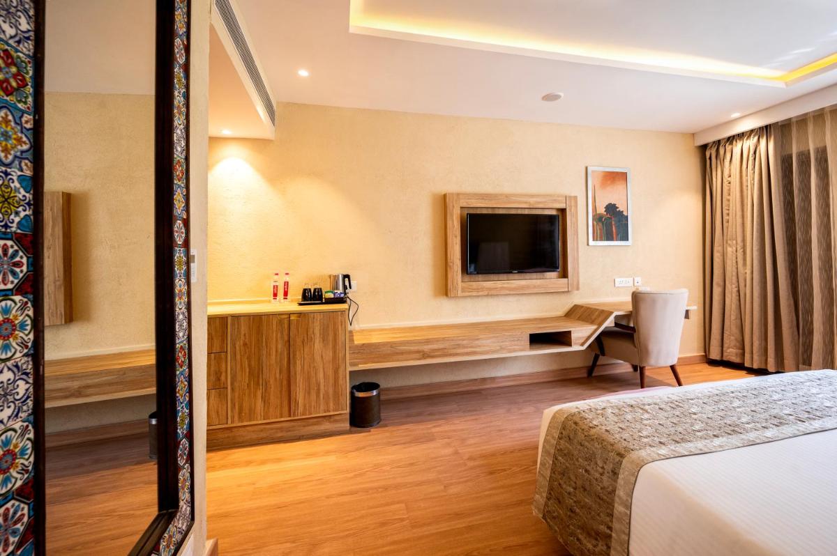 a hotel room with a bed and a desk and a tv at Essentia Luxury Resort & Spa Udaipur in Udaipur
