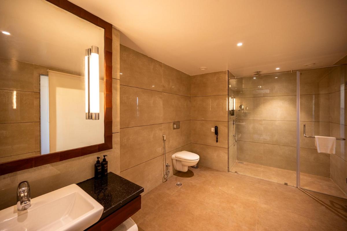 a bathroom with a shower and a toilet and a sink at Essentia Luxury Resort & Spa Udaipur in Udaipur