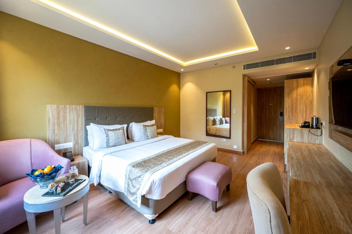 a bedroom with a large bed and a living room at Essentia Luxury Resort & Spa Udaipur in Udaipur