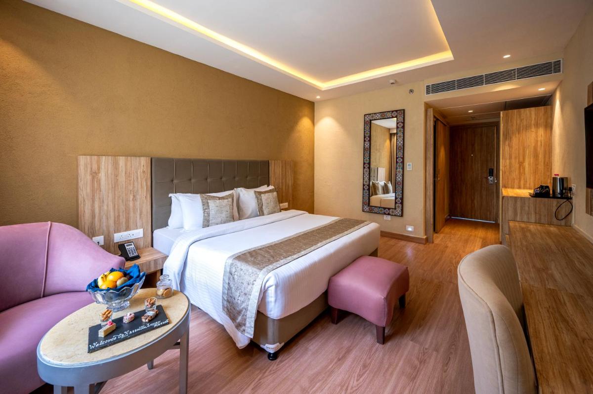 a hotel room with a large bed and a table at Essentia Luxury Resort & Spa Udaipur in Udaipur
