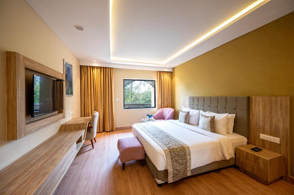 a hotel room with a bed and a television at Essentia Luxury Resort & Spa Udaipur in Udaipur