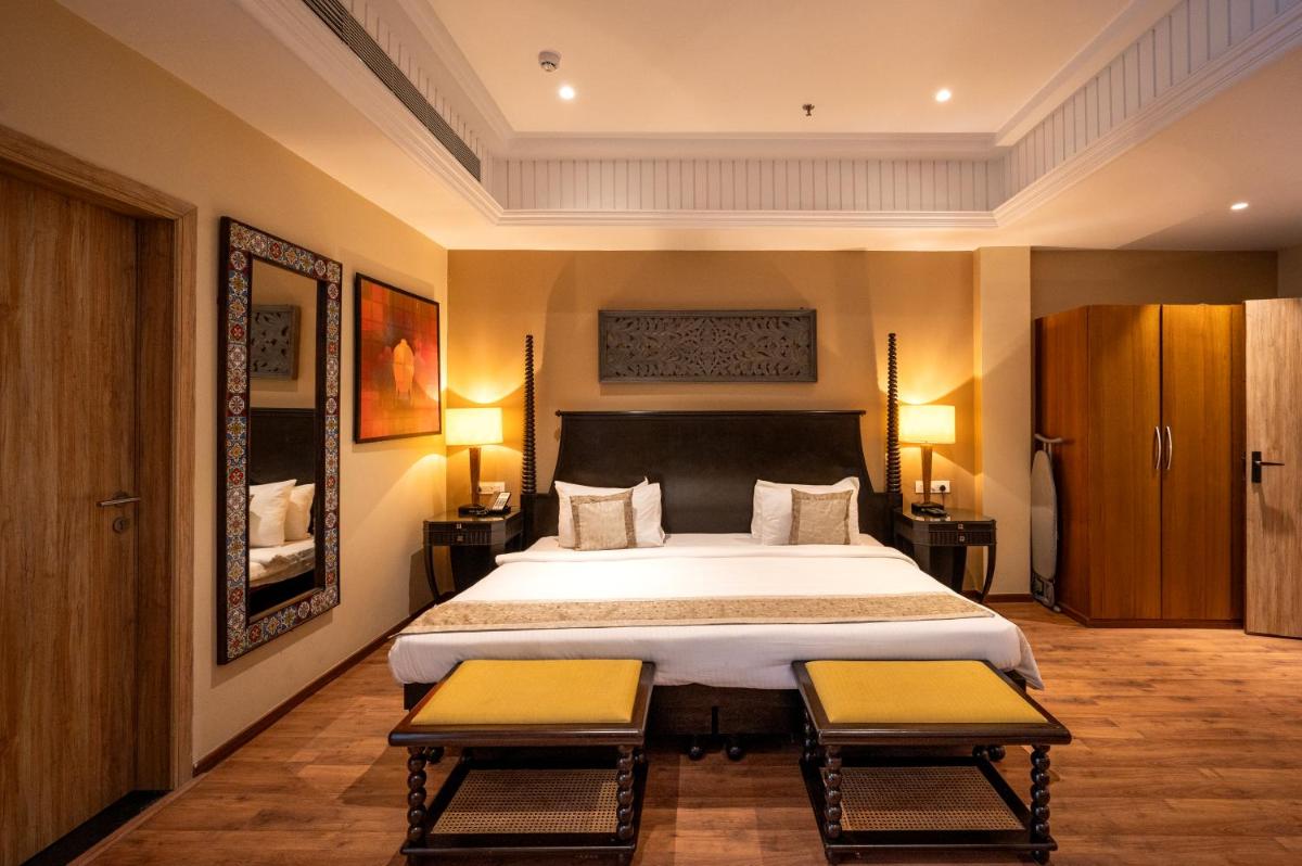 a bedroom with a large bed with two benches in it at Essentia Luxury Resort & Spa Udaipur in Udaipur