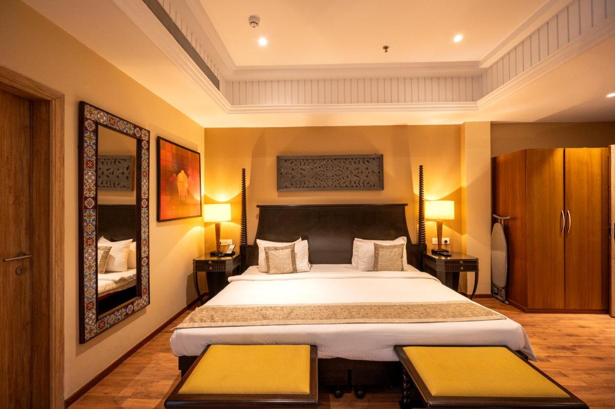 a bedroom with a large bed with two tables at Essentia Luxury Resort & Spa Udaipur in Udaipur