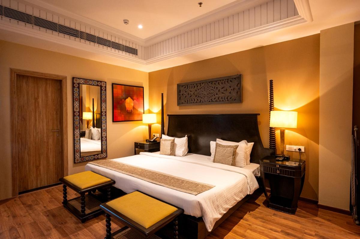 a bedroom with a large bed and two chairs at Essentia Luxury Resort & Spa Udaipur in Udaipur