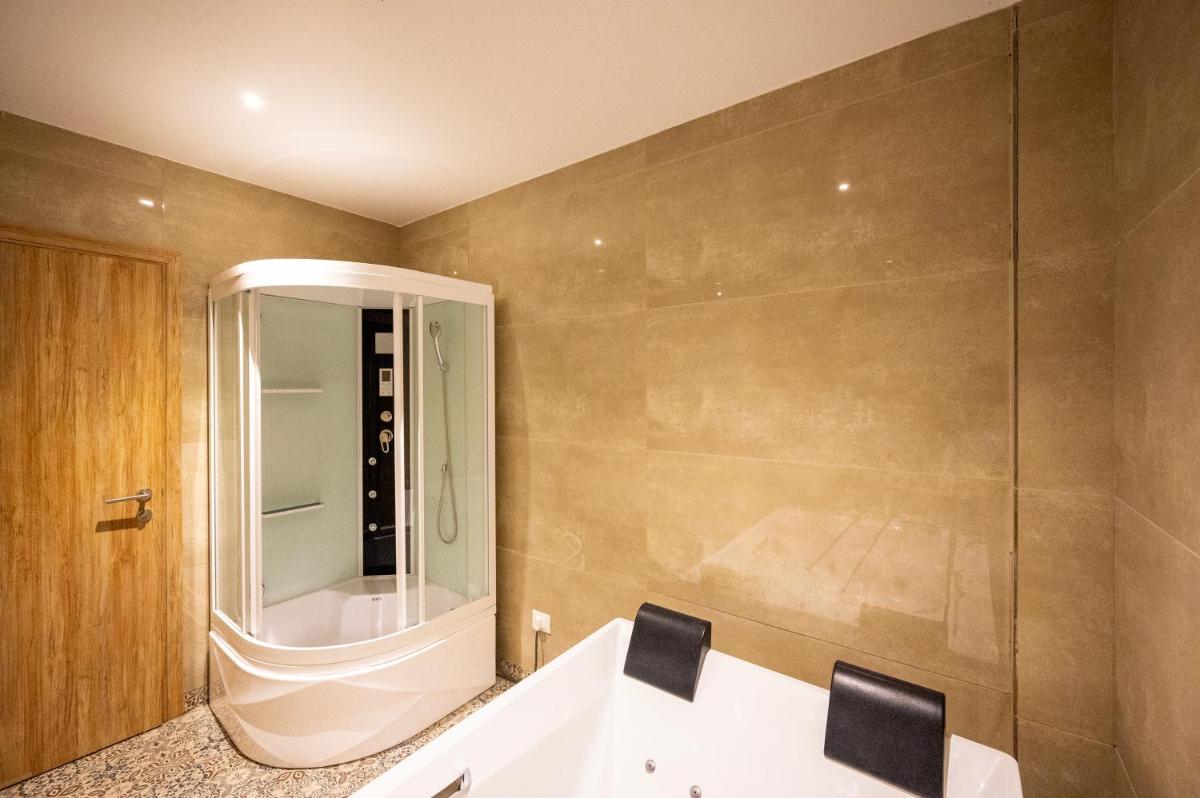 a bathroom with a tub and a glass shower at Essentia Luxury Resort & Spa Udaipur in Udaipur