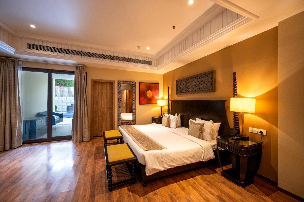 a bedroom with a large bed and a table and chairs at Essentia Luxury Resort & Spa Udaipur in Udaipur