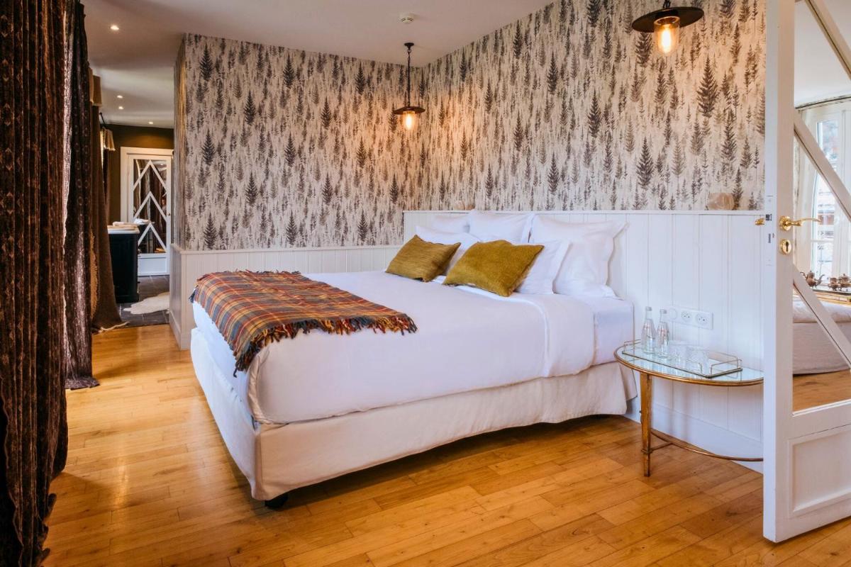 une chambre avec un lit blanc et un mur recouvert de papier peint dans l'établissement Grand Hotel Soleil d'Or, à Megève
