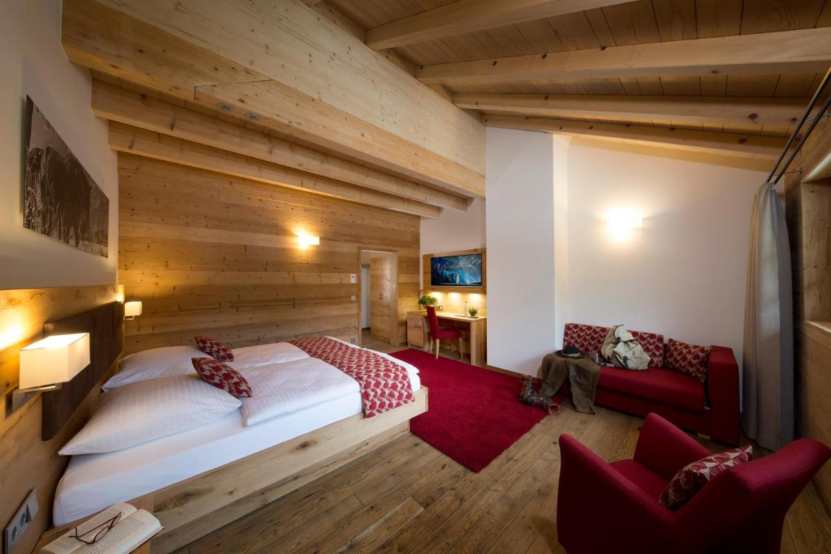 ein Schlafzimmer mit einem großen Bett und einer roten Couch in der Unterkunft Gästehaus der Geroldsauer Mühle in Baden-Baden
