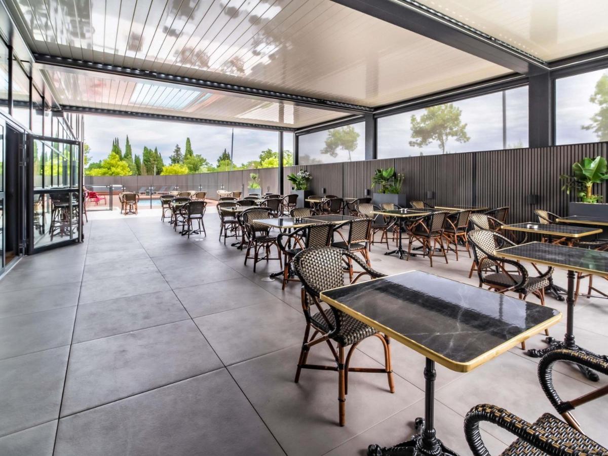 un restaurant vide avec des tables, des chaises et des fenêtres dans l'établissement ibis Styles Castelnaudary, à Castelnaudary