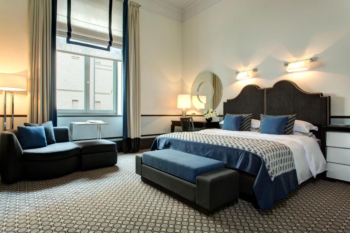 ein Schlafzimmer mit einem Bett, einem Stuhl und einem Spiegel in der Unterkunft Hotel De Rome Berlin in Berlin
