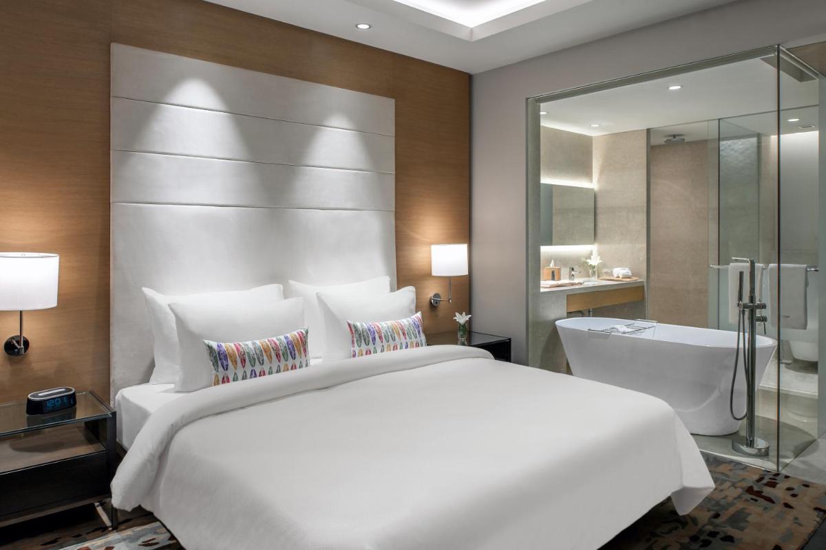 a bedroom with a large white bed and a bath tub at Feathers- A Radha Hotel, Chennai in Chennai