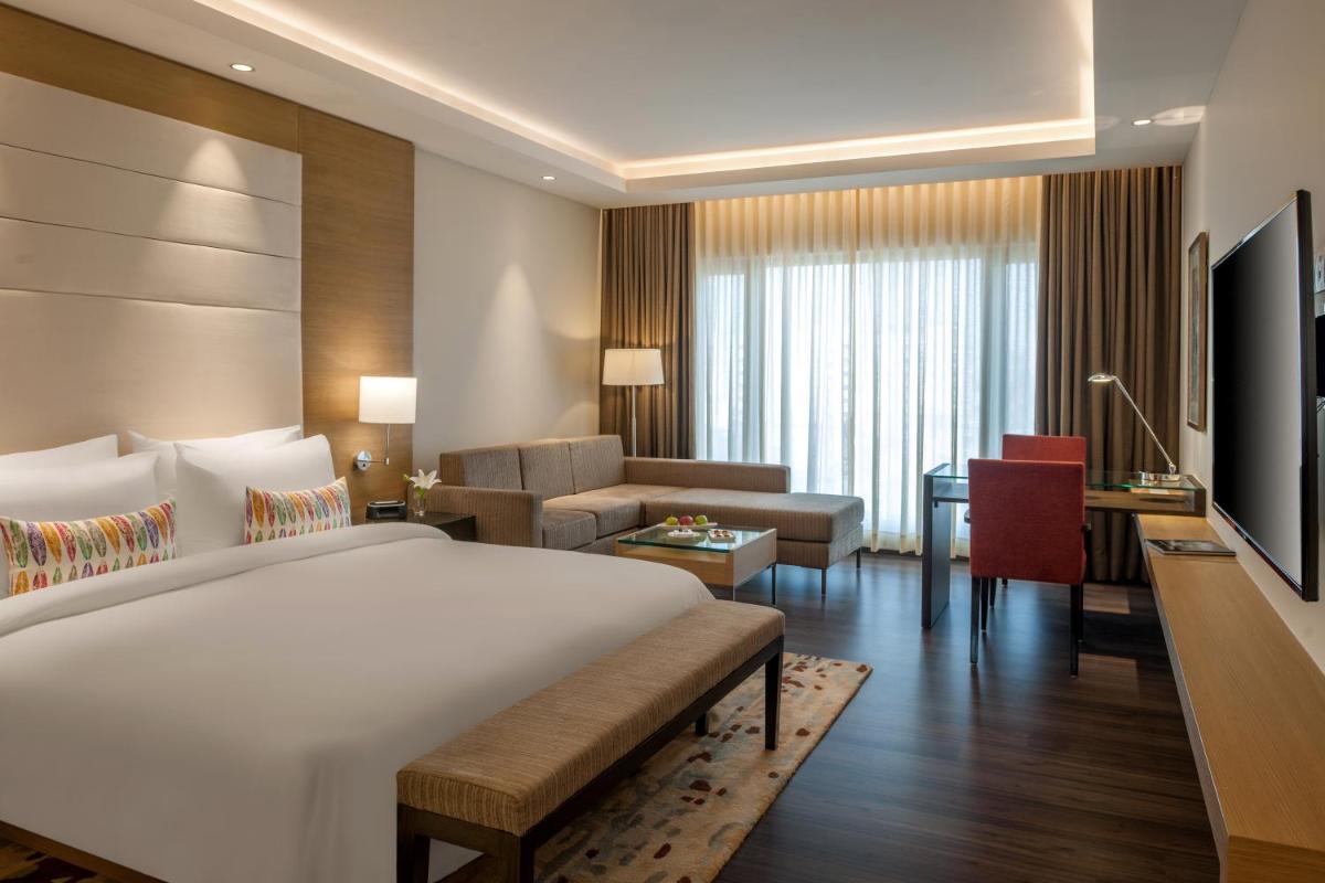a bedroom with a large bed and a living room at Feathers- A Radha Hotel, Chennai in Chennai