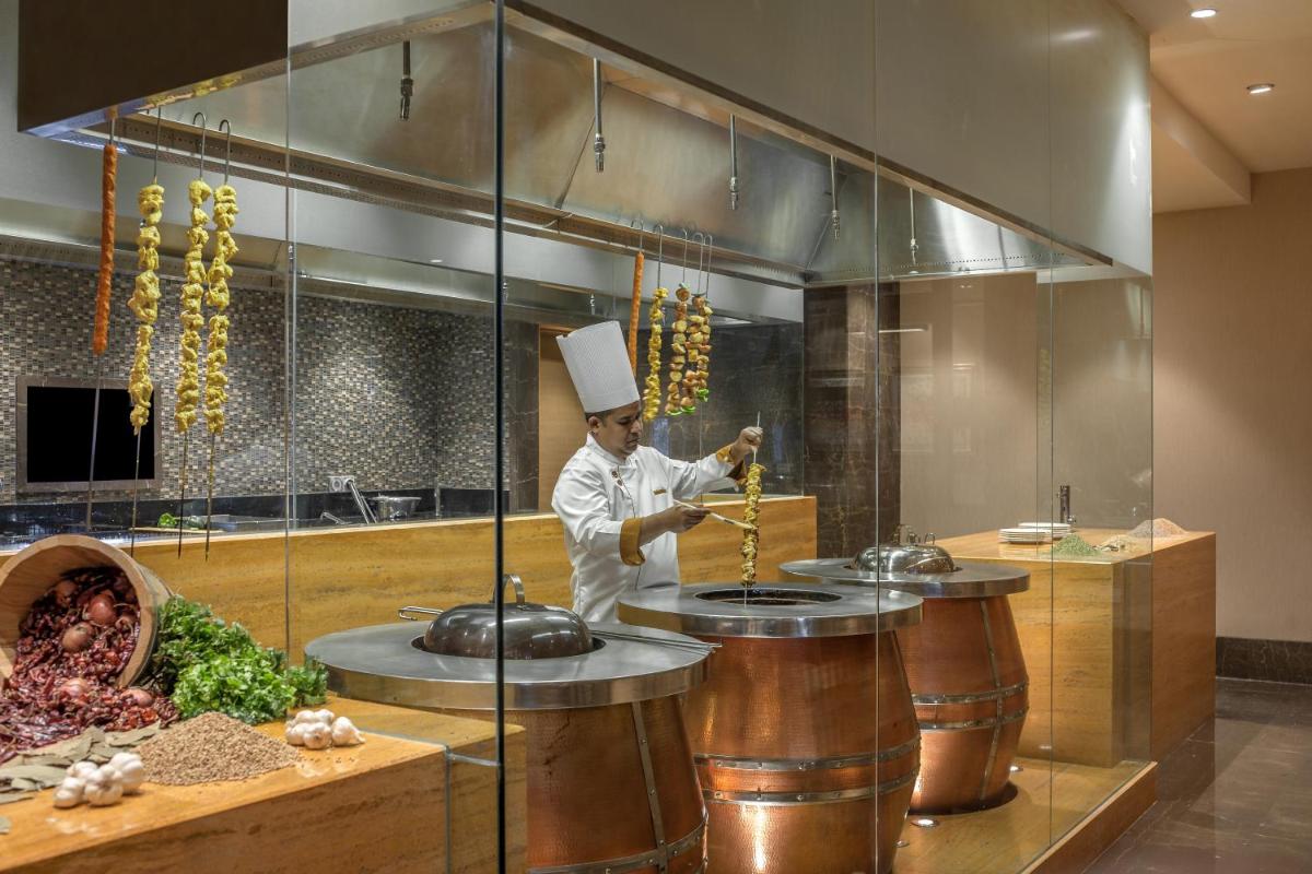a chef standing in a kitchen preparing food at Feathers- A Radha Hotel, Chennai in Chennai