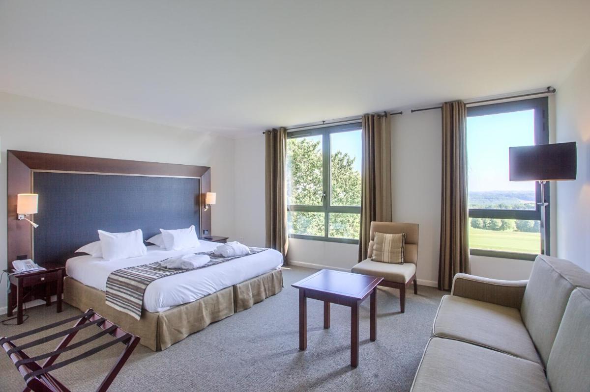 une chambre d'hôtel avec un lit et un canapé dans l'établissement Hôtel du Golf, à Lumbres