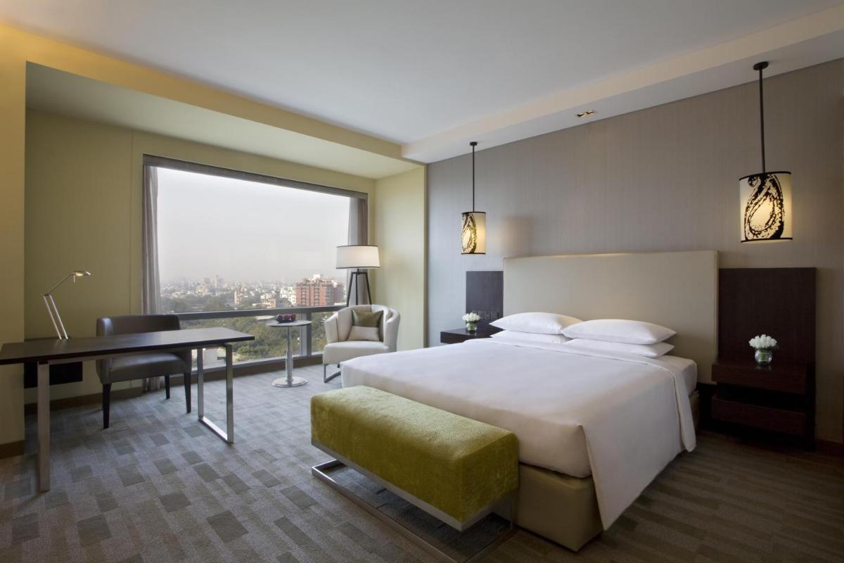 a hotel room with a bed and a desk and a window at Hyatt Regency Ahmedabad in Ahmedabad