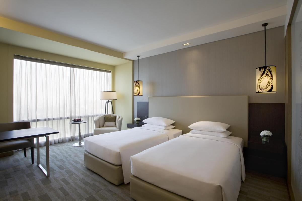 a hotel room with two beds and a desk at Hyatt Regency Ahmedabad in Ahmedabad