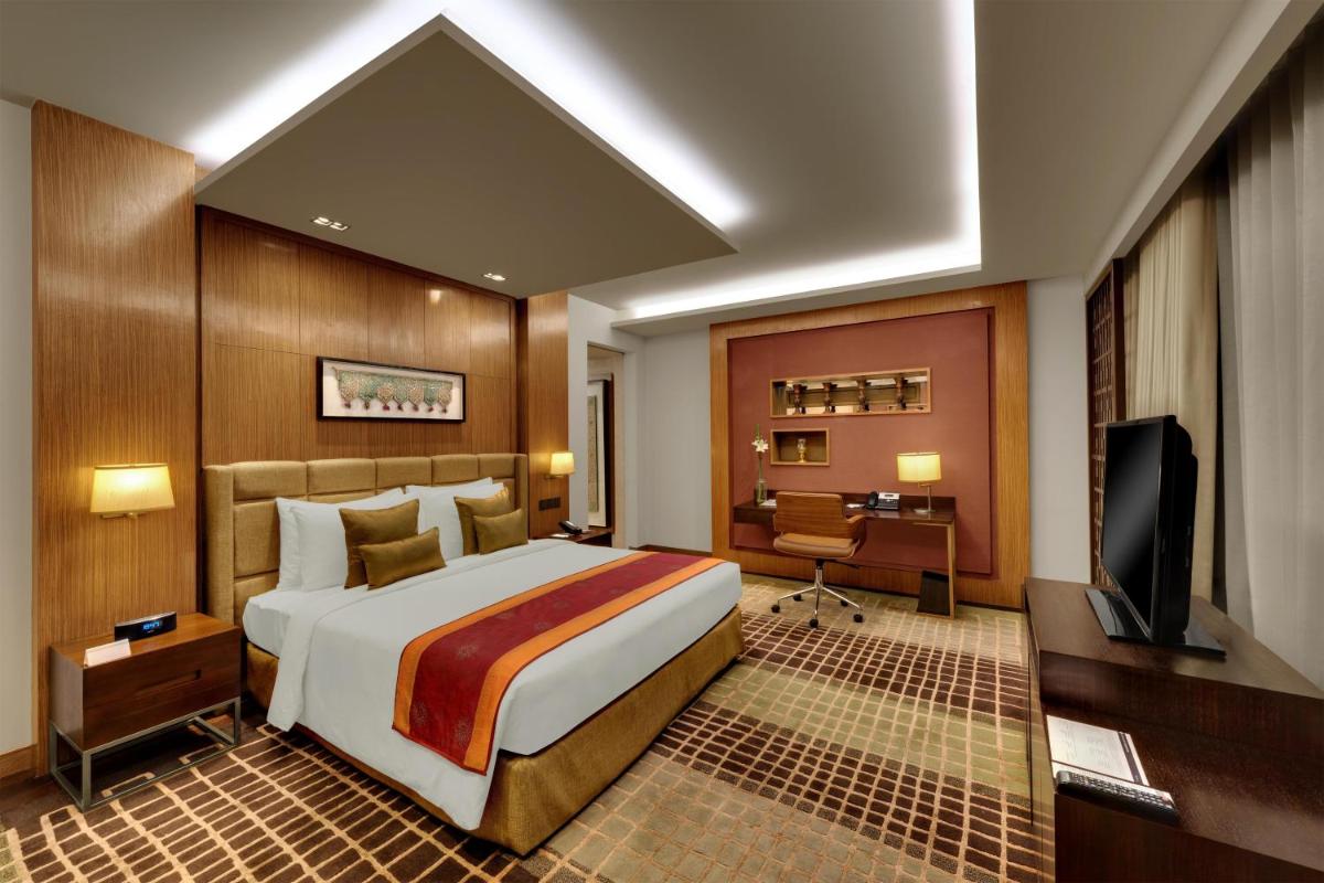 a bedroom with a large bed and a television at Hyatt Regency Ahmedabad in Ahmedabad