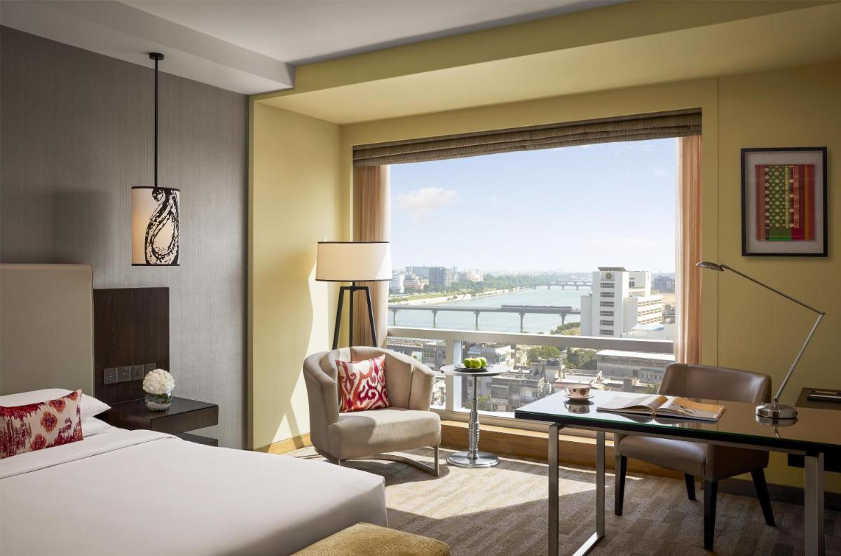 a hotel room with a bed and a desk and a window at Hyatt Regency Ahmedabad in Ahmedabad