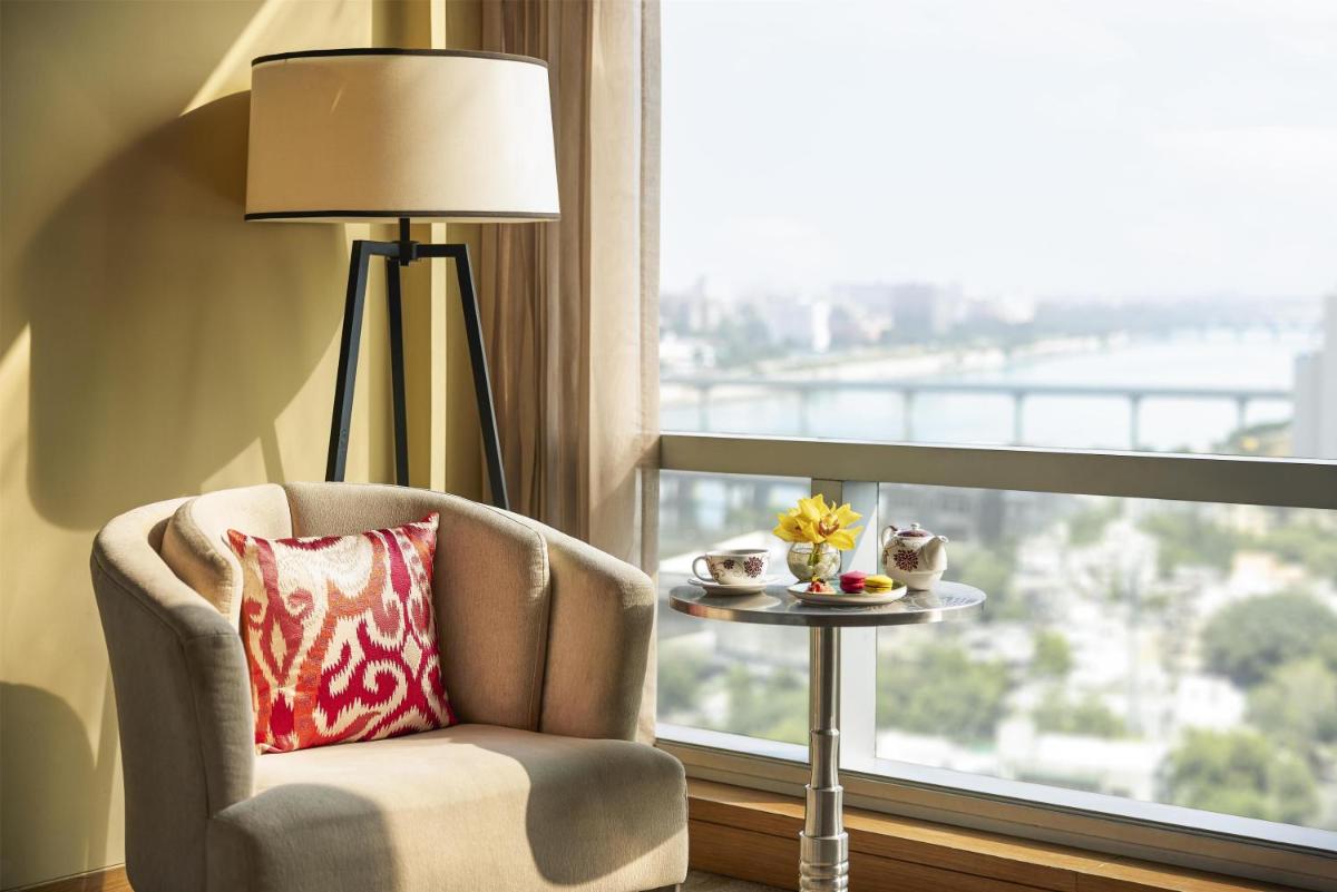 a chair and a lamp in a room with a window at Hyatt Regency Ahmedabad in Ahmedabad