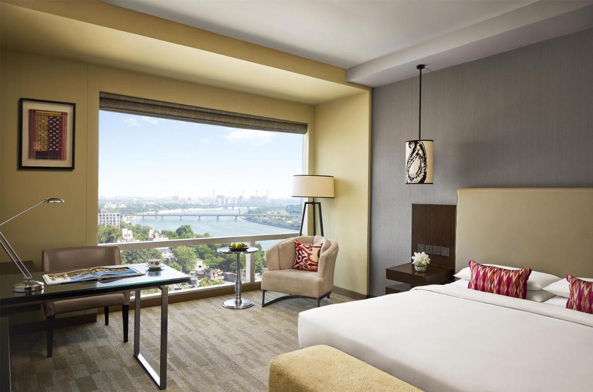 a hotel room with a bed and a desk and a window at Hyatt Regency Ahmedabad in Ahmedabad
