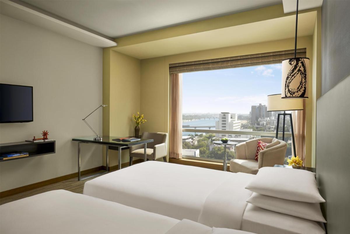 a hotel room with a bed and a desk and a window at Hyatt Regency Ahmedabad in Ahmedabad