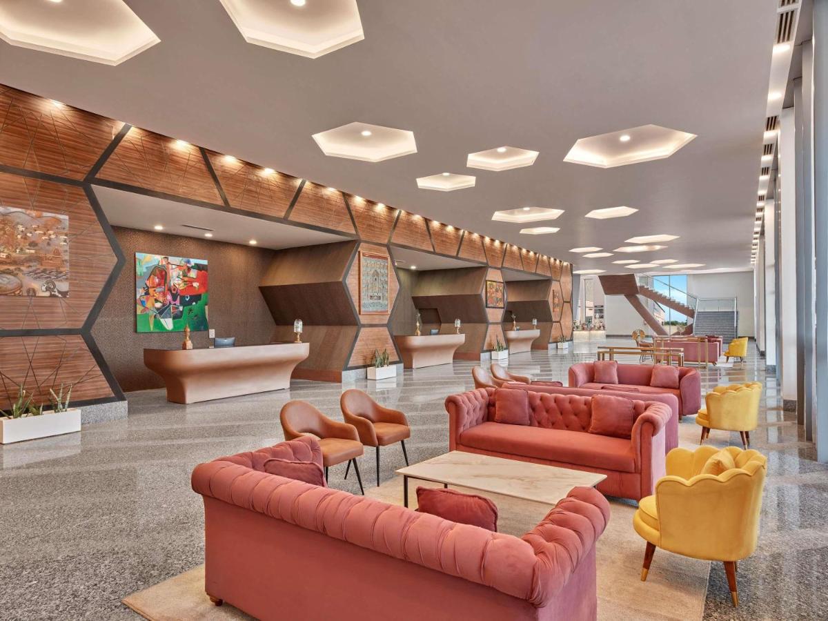a lobby with red leather couches and chairs at Novotel Jaipur Convention Centre in Jaipur