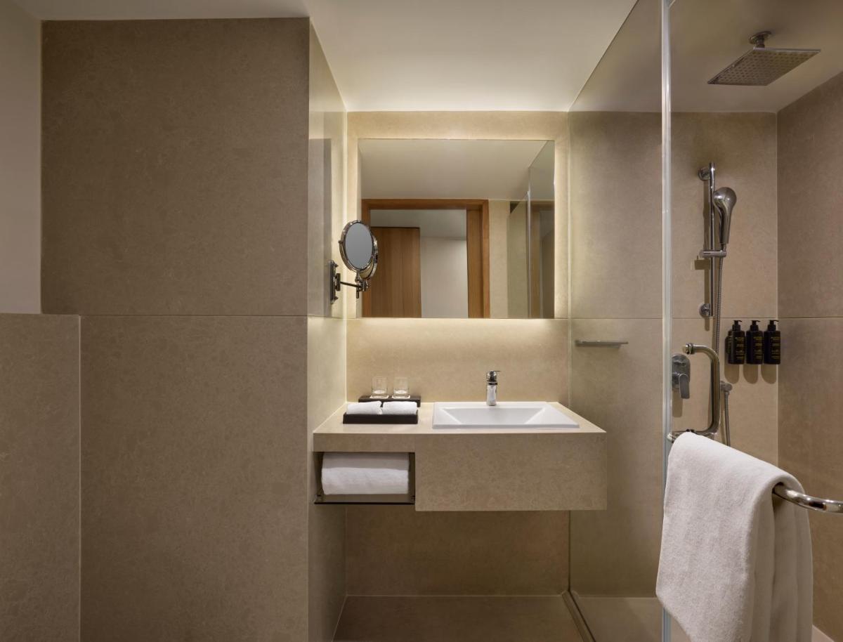 a bathroom with a sink and a mirror at The Fern Mumbai, Goregaon, Series by Marriott in Mumbai a bathroom with a sink and a mirror at The Fern Mumbai, Goregaon, Series by Marriott in Mumbai