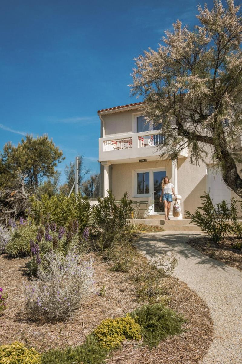 un couple marchant devant une maison dans l'établissement Les appartements de l'Helios - Ile des Embiez, à Six-Fours-les-Plages